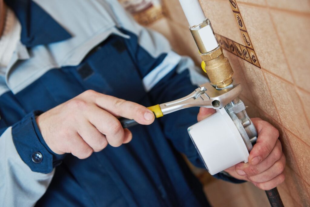 Worker holding a wrench on a water pipe