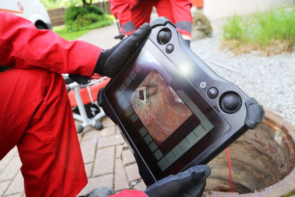 hands holding a portable CCTV screen for drain inspection