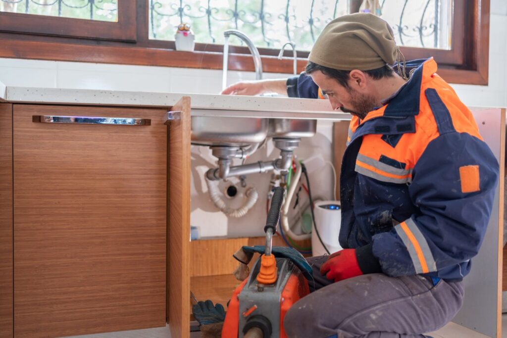 Man fixing kitchen sink drain pipes